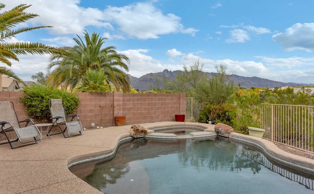 Backyard pool and spa with lounge chairs, palm trees, mountain view, and desert landscape
